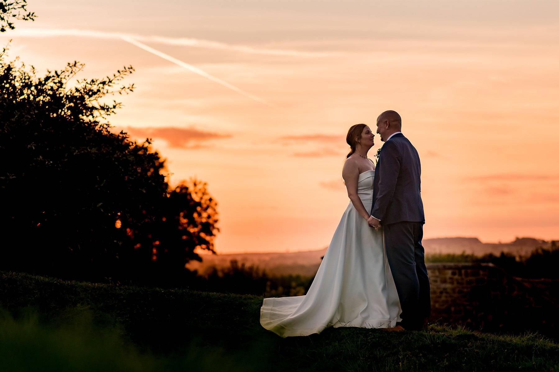 Bride and Groom Standing in front of a Sunset at The Barns at Hunsbury Hill